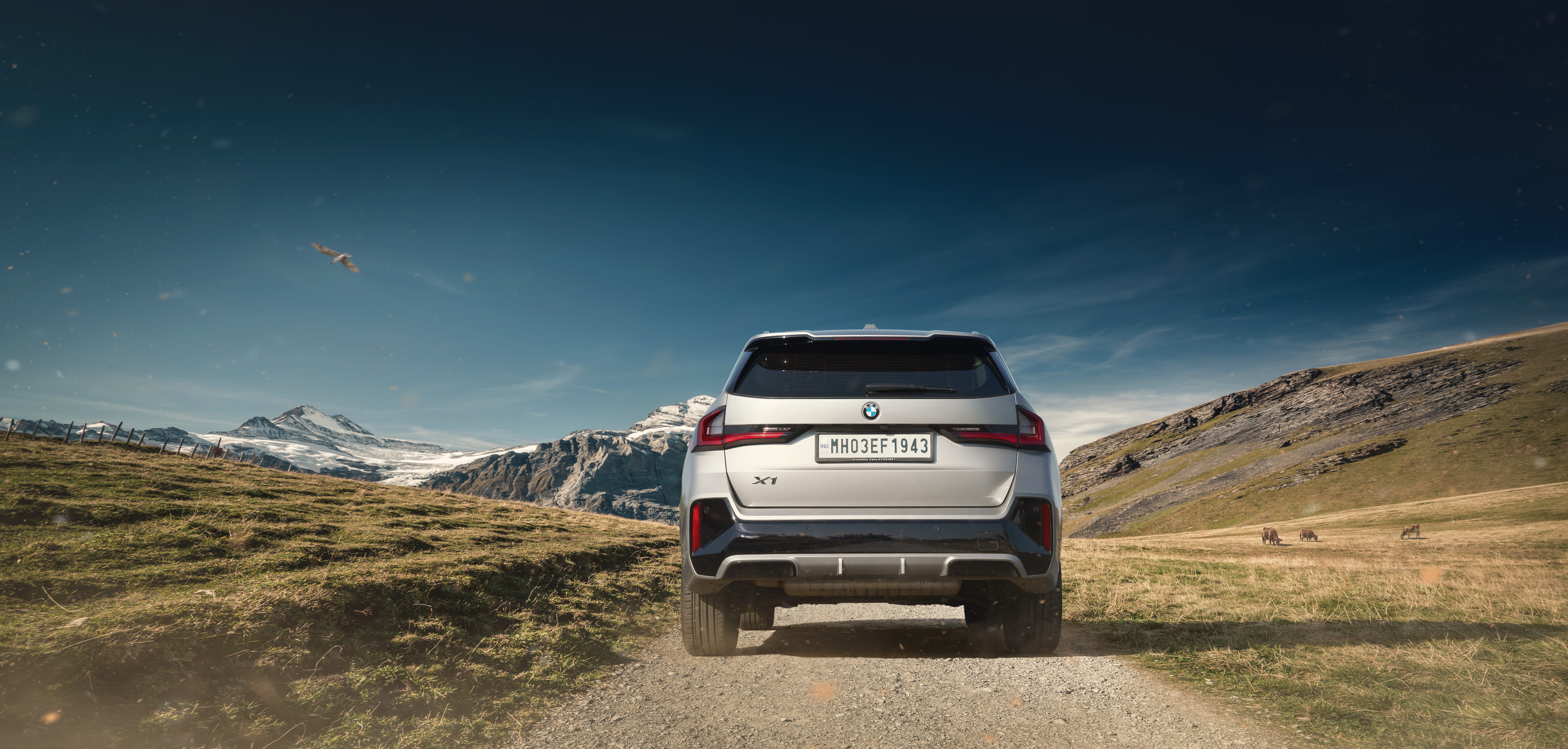 BMW X1 on a mountain track beneath a deep blue sky